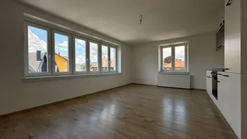 Lichtdurchfluteter Wohnbereich mit großen Fenstern und Blick auf die umliegenden Dächer.