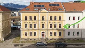 Historisches Gebäude mit gelber Fassade, roten Ziegeldächern und Solarpaneelen auf dem Dach.