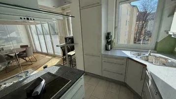 Helle Küche mit Fenster, Spüle und Einbaugeräten, Blick ins Grüne.