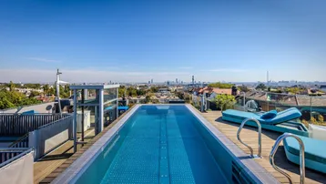 Moderner Infinity-Pool auf der Dachterrasse mit weitem Blick über die Stadt.