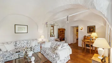 Gemütliches Wohnzimmer mit weiß getünchten Gewölbedecken, floralen Sofas und Holzboden.