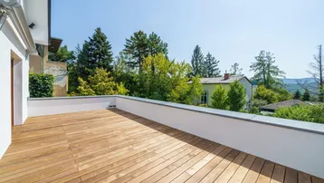 Große Holzterrasse mit weitem Blick ins Grüne und auf die umliegende Landschaft.