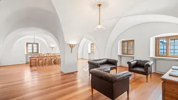 Geräumiger Wohn- und Essbereich mit Gewölbedecken, Holzboden und traditionellen Ledersofas.