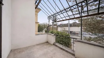 Überdachter Balkon mit schmiedeeisernem Geländer und Blick auf die Umgebung.