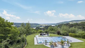 Großzügiger Gartenbereich mit Pool, Liegeflächen und atemberaubendem Weitblick über die Landschaft.