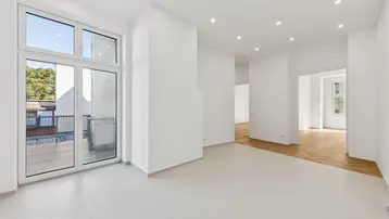 Helles, offenes Wohnzimmer mit Zugang zum Balkon und teilweise Fliesenboden.