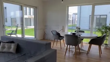 Lichtdurchfluteter Wohn- und Essbereich mit Holzboden und Blick auf die grüne Außenanlage.