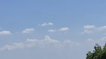 Weitläufiger Panoramablick über eine Stadt mit Kirchturm und einem See in der Ferne.