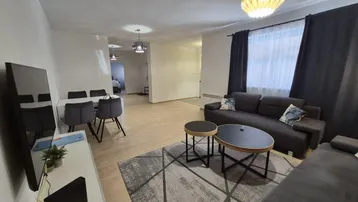 Geräumiger Wohn- und Essbereich mit modernem Sofa, Couchtischen und hellem Holzboden.