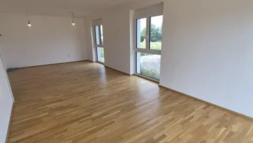 Helles, leeres Zimmer mit Parkettboden und großen Fenstern, bereit zum Einzug.