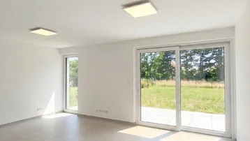 Geräumiger, lichtdurchfluteter Wohnbereich mit großen Fenstern und Blick ins Grüne.