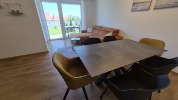 Heller Wohn- und Essbereich mit Holzboden, modernem Sofa und direktem Zugang zum Garten.