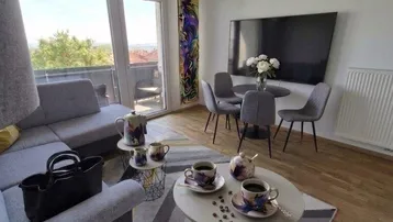 Heller offener Wohn- und Essbereich mit modernem Sofa, Holzboden und Zugang zum Balkon.