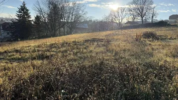 Sonniges Grundstück mit weitem Blick über die Landschaft und umliegende Bebauung.