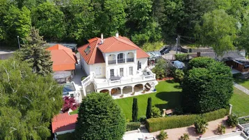 Luxuriöse Villa am See mit großem Garten, privatem Bootsanleger und üppiger Vegetation.