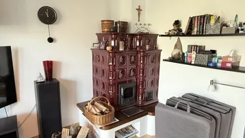 Gemütlicher Wohnbereich mit traditionellem Kachelofen und rustikalen Dekorationselementen.