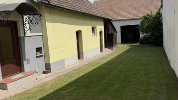 Langer Rasenbereich neben einem Gebäude mit traditionellem Ziegeldach und Eingangsbereich.
