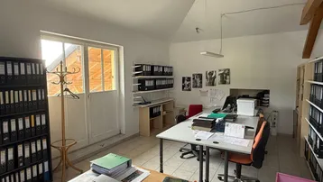 Helles Büro mit mehreren Arbeitsplätzen, Aktenregalen und natürlichem Lichteinfall durch große Fenster.