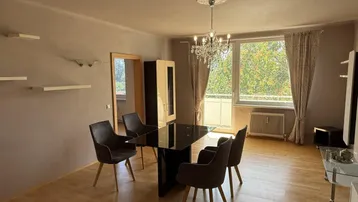 Geräumiger Wohn- und Essbereich mit großem Fenster, das viel Tageslicht und einen grünen Ausblick bietet.