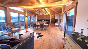 Geräumiger offener Wohn- und Essbereich mit Holzbalkendecke, großen Fenstern und Zugang zur Terrasse.