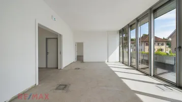 Heller, leerer Büroraum mit großen Fensterfronten, viel Tageslicht und Blick ins Grüne.
