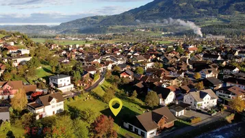 Luftaufnahme der Wohngegend mit Bergen im Hintergrund und markiertem Grundstück.