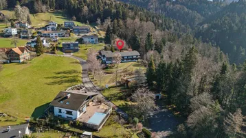 Luftaufnahme eines Anwesens mit Pool und umliegender grüner Landschaft, umgeben von Wald.