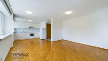 Heller offener Wohn- und Essbereich mit integrierter Küche und Parkettboden.