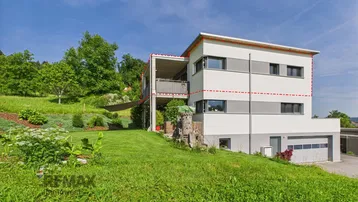Modernes Wohnhaus mit Balkonen, Garage und weitläufigem Garten in grüner Umgebung.