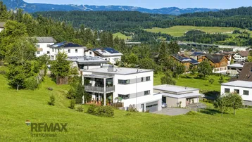 Panoramablick auf das moderne Wohnhaus eingebettet in eine grüne Berglandschaft.