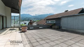 Große Dachterrasse mit Fliesenboden und weitem Blick auf die umliegende Berglandschaft.