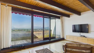 Helles Wohnzimmer mit Holzbalkendecke, Parkettboden und weitem Blick über die Stadt und Berge.