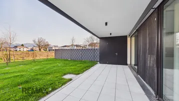 Überdachte Terrasse mit Fliesenboden und Blick auf den privaten Gartenbereich.