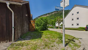 Ländliche Straße mit Grünflächen und Blick auf die umliegenden Berge, bietet eine ruhige Umgebung.
