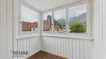 Heller, verglaster Balkon mit Holzverkleidung und weitem Blick auf die umliegende Berglandschaft.