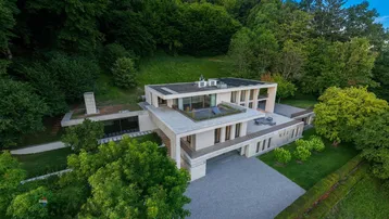 Luftaufnahme der weitläufigen modernen Villa mit Flachdach und Terrassen, eingebettet in die Natur.