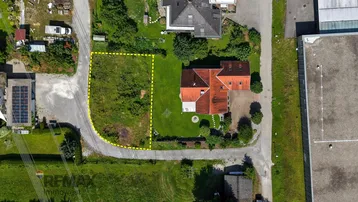 Luftaufnahme eines Baugrundstücks, umgeben von Wohnhäusern und viel Grün in ländlicher Umgebung.