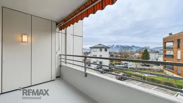 Geräumiger Balkon mit Markise und weitem Blick auf die umliegende Berglandschaft.