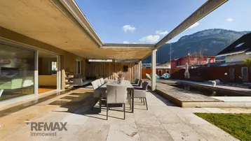 Geräumige Terrasse mit großem Esstisch und Blick auf die Berge, ideal für Mahlzeiten im Freien.
