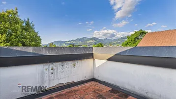 Dachterrasse mit Bergblick und Ziegelboden, ideal für sonnige Stunden im Freien.