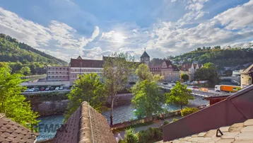 Panoramablick über die Stadt mit Fluss, historischen Gebäuden und grünen Hügeln.