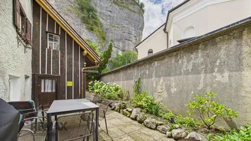 Gemütliche Terrasse mit Sitzgelegenheiten und Blick auf die beeindruckende Felswand.