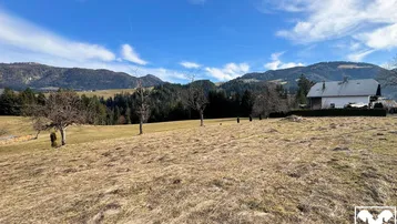 Weitläufiges Grundstück mit Blick auf die umliegende Berglandschaft und ein traditionelles Haus.