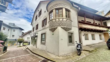 Altes Gebäude mit traditionellem Erker und Holzbalkon in einer städtischen Gasse.
