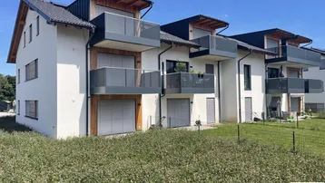 Moderne Wohnanlage mit mehreren Balkonen und Holzverkleidung unter blauem Himmel.
