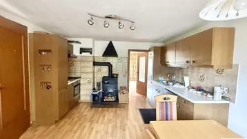 Traditionelle Küche mit Holzschränken, gefliestem Spritzschutz und einem gemütlichen Holzofen.