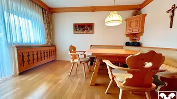 Traditioneller Essbereich mit Holztisch, Eckbank und Parkettboden, umgeben von rustikalen Holzelementen.