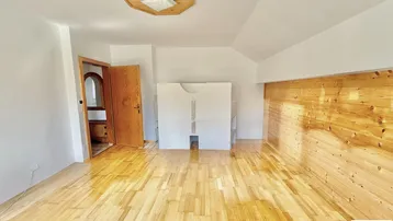 Helles Zimmer mit Holzboden und einer Holzwandverkleidung, ideal als Schlafzimmer nutzbar.