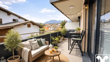 Möblierter Balkon mit Bergblick, vielen Pflanzen und gemütlicher Sitzecke für entspannte Stunden.