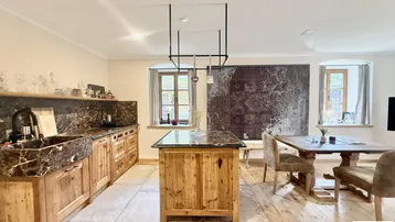 Rustikale Küche mit dunklen Steinplatten, Holzschränken und einem Essbereich im offenen Wohnkonzept.